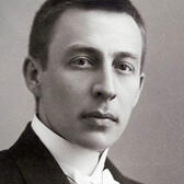 Black-and-white headshot picture of young Rachmaninoff, to staring to the camera.